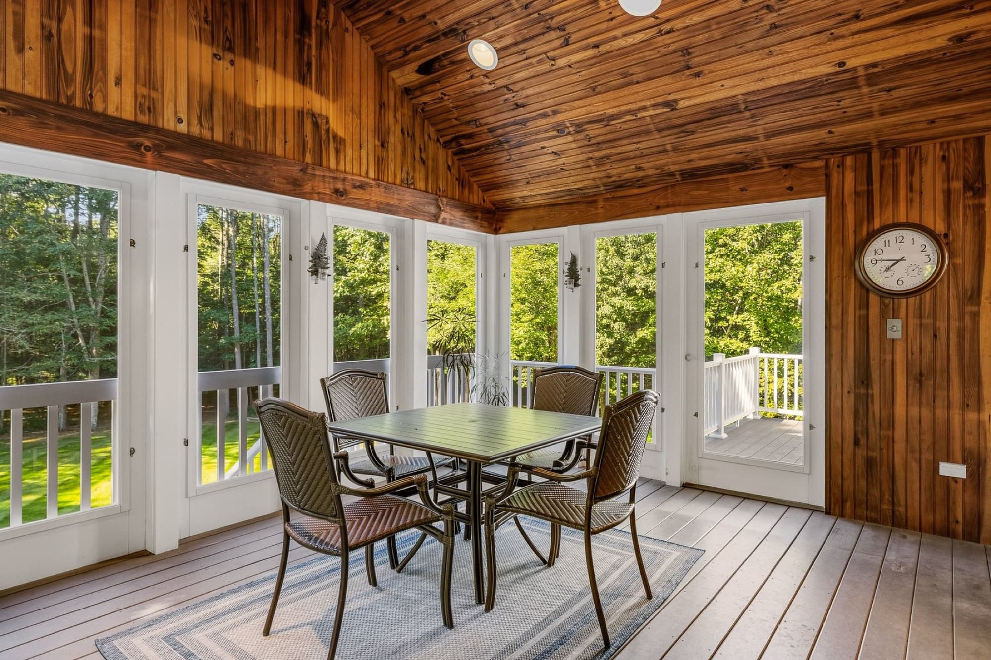 The 3-season porch with a knotty pine ceiling, windows on 3 sides, and a table for 4